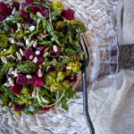 beet and broccoli salad topped with sunflower seeds and served on a glass dinner plate