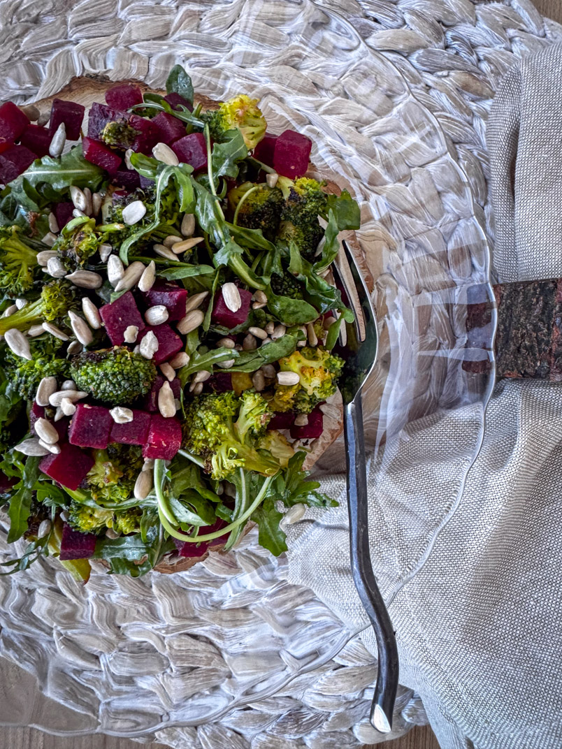 beet and broccoli salad topped with sunflower seeds and served on a glass dinner plate