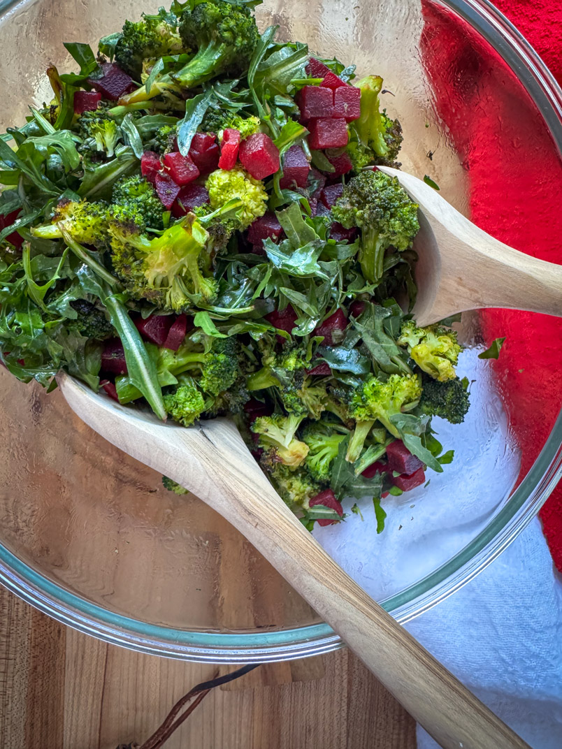 a serving dish with roasted broccoli, arugula, and beet dinner salad